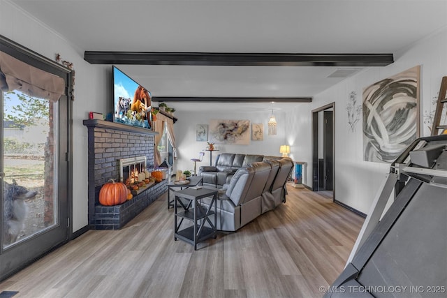 living room featuring a brick fireplace, light hardwood / wood-style floors, and beamed ceiling