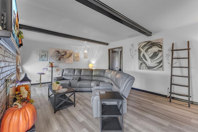 living room with a fireplace, beam ceiling, and light hardwood / wood-style floors