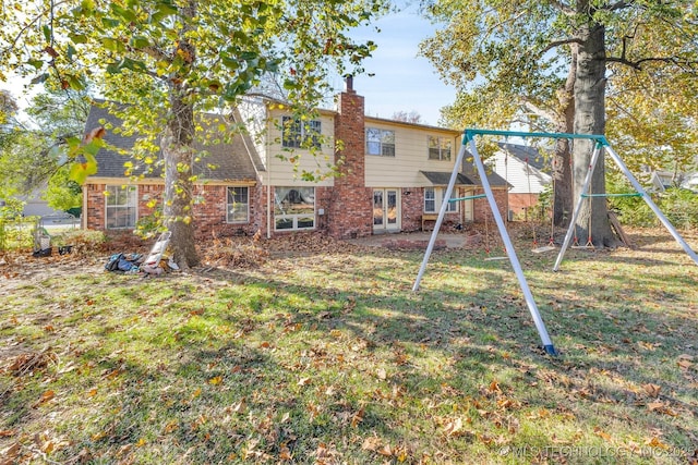 back of house featuring a playground and a lawn