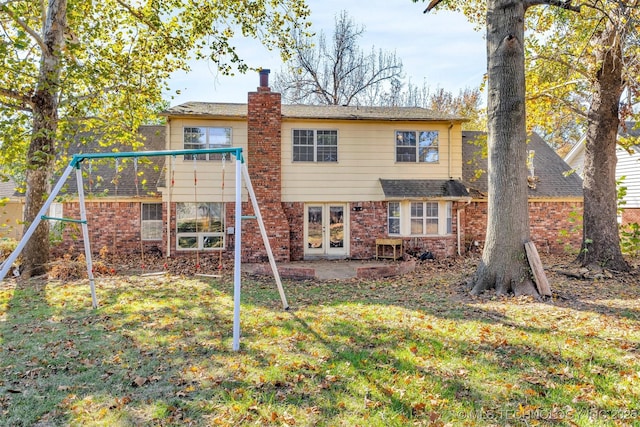 rear view of house with a yard, a patio, a playground, and french doors