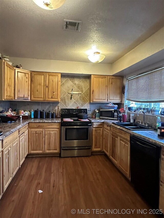 kitchen featuring sink, a textured ceiling, dark hardwood / wood-style flooring, stainless steel appliances, and decorative backsplash