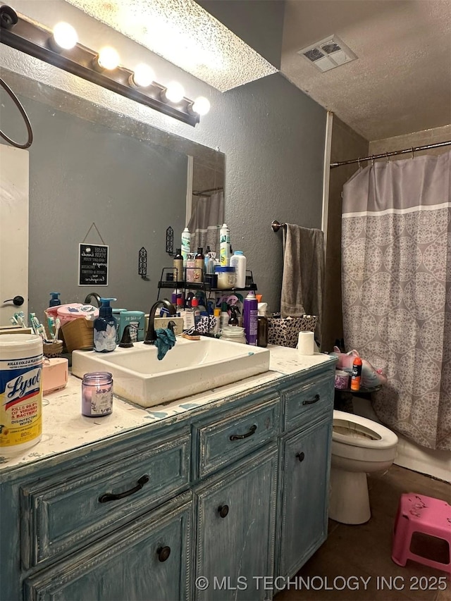 bathroom with vanity, curtained shower, a textured ceiling, and toilet