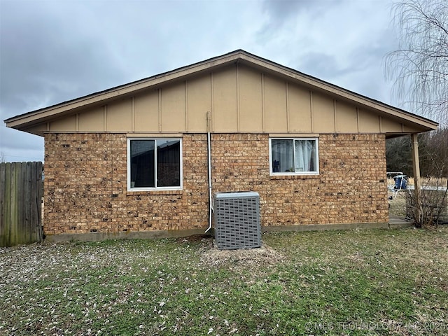 view of side of property featuring cooling unit and a lawn