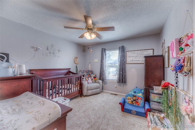 bedroom with a nursery area, ceiling fan, light carpet, and a textured ceiling