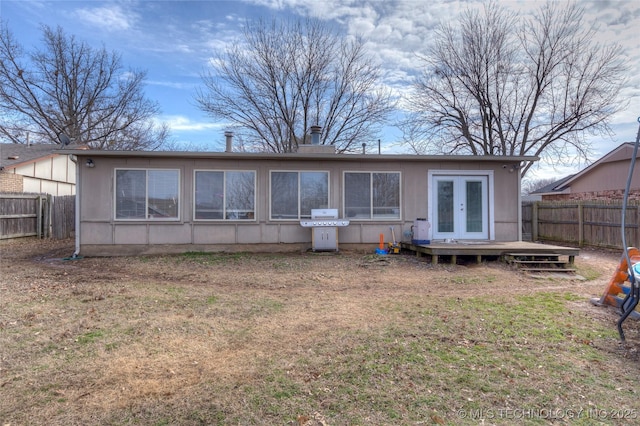 rear view of property featuring a yard, a deck, and french doors