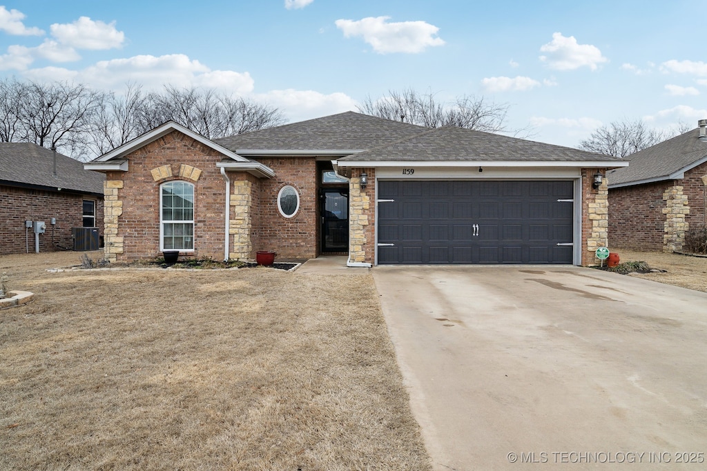 ranch-style home featuring driveway, a shingled roof, an attached garage, central air condition unit, and brick siding