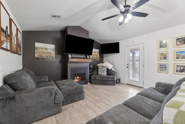 living room with ceiling fan, lofted ceiling, and light hardwood / wood-style floors