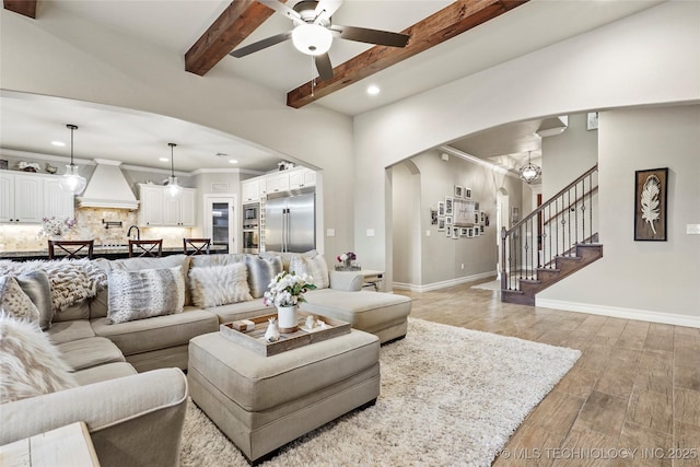 living room with wood-type flooring, crown molding, ceiling fan, and beam ceiling