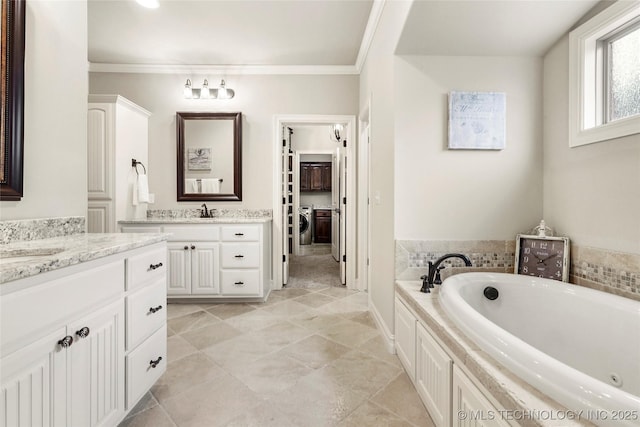 bathroom featuring independent washer and dryer, ornamental molding, a bathing tub, and vanity