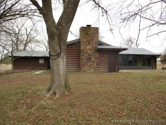 back of property featuring a sunroom and a lawn