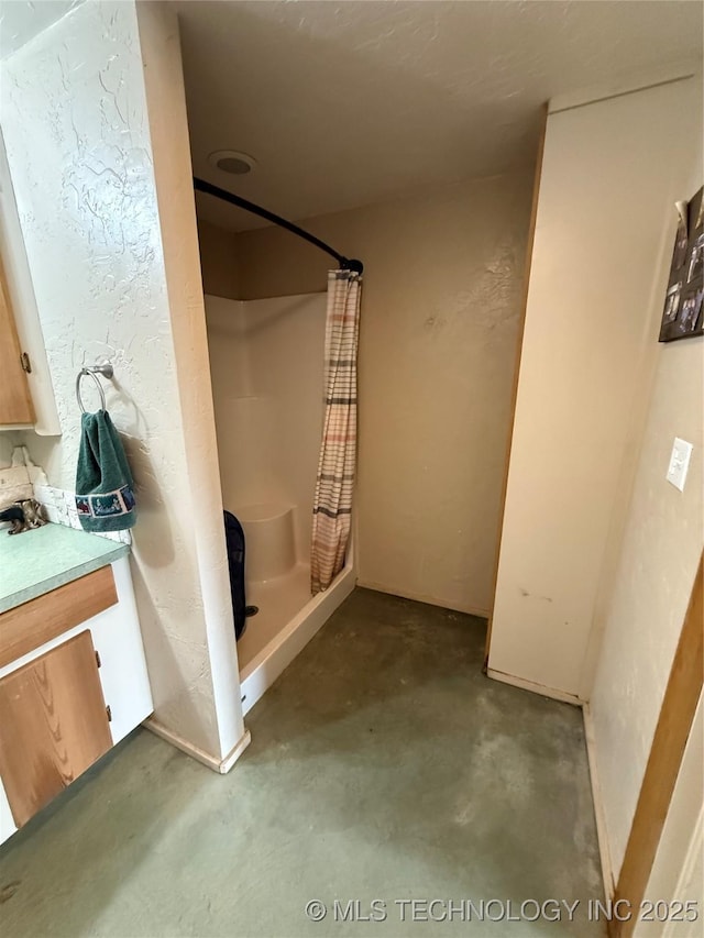 bathroom featuring unfinished concrete flooring, a stall shower, and vanity