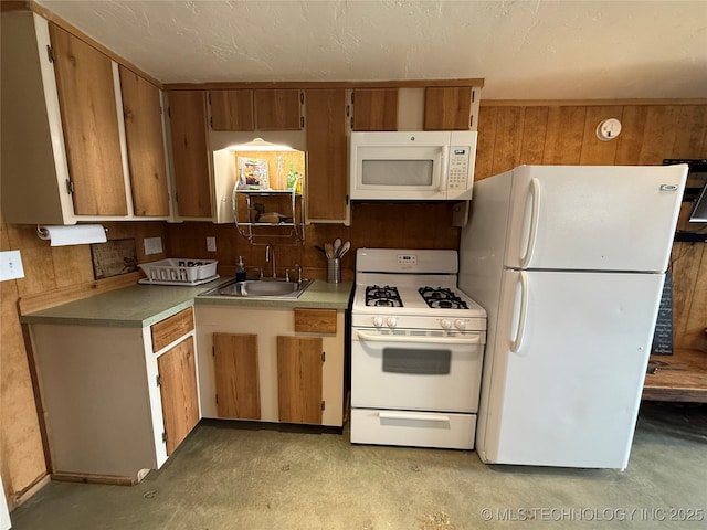 kitchen featuring a sink, white appliances, wooden walls, and concrete flooring