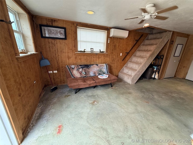 unfurnished living room with a wall mounted air conditioner, plenty of natural light, and wood walls