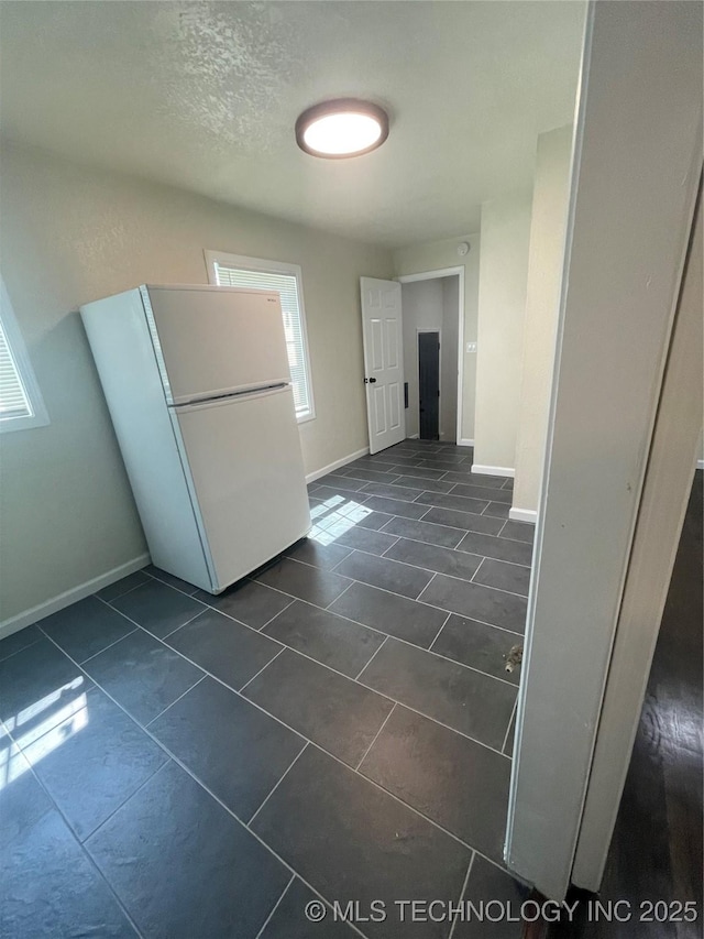 interior space with dark tile patterned flooring, a textured ceiling, and baseboards