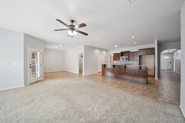 unfurnished living room with ceiling fan and carpet floors