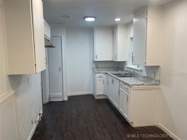 kitchen featuring sink, decorative backsplash, dark wood-type flooring, and white cabinets