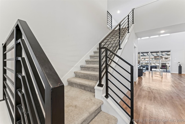 stairway featuring hardwood / wood-style flooring and a towering ceiling