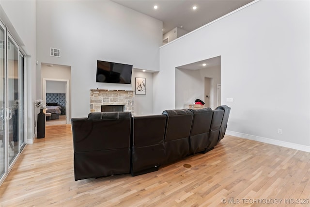 living room featuring a fireplace, light hardwood / wood-style flooring, and a high ceiling