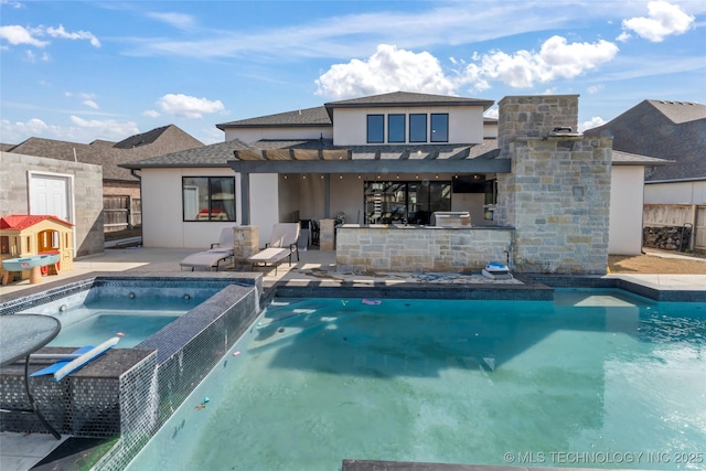 rear view of property with a swimming pool with hot tub, a pergola, a patio, an outdoor kitchen, and exterior bar