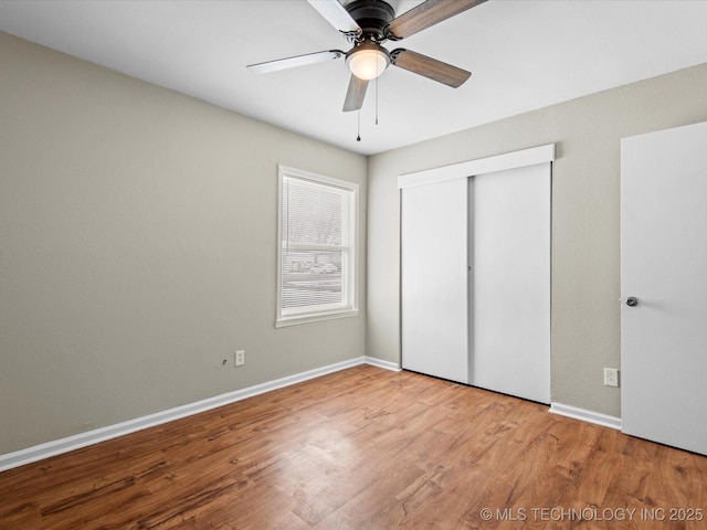 unfurnished bedroom with a ceiling fan, wood finished floors, a closet, and baseboards