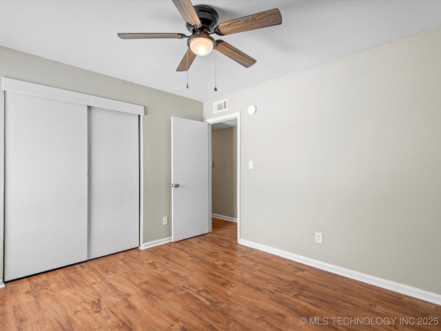 unfurnished bedroom with visible vents, baseboards, wood finished floors, a closet, and a ceiling fan