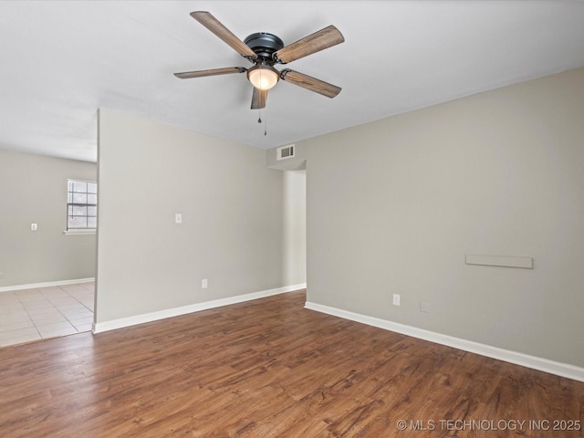 spare room featuring visible vents, a ceiling fan, baseboards, and wood finished floors