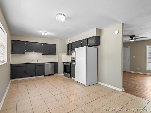 kitchen with a sink, dark cabinetry, stainless steel appliances, light countertops, and light tile patterned floors