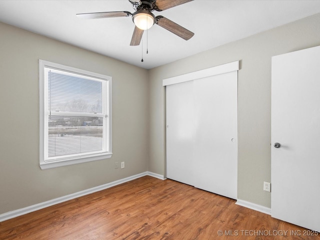 unfurnished bedroom featuring a closet, ceiling fan, baseboards, and wood finished floors