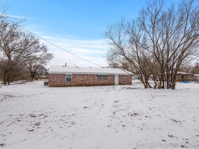 snow covered house featuring a garage and brick siding