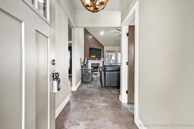 corridor with lofted ceiling, concrete flooring, and a chandelier