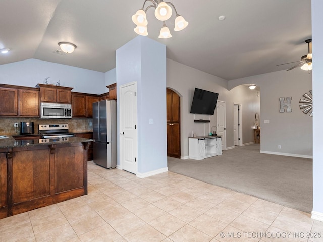 kitchen with decorative light fixtures, decorative backsplash, ceiling fan, stainless steel appliances, and light carpet