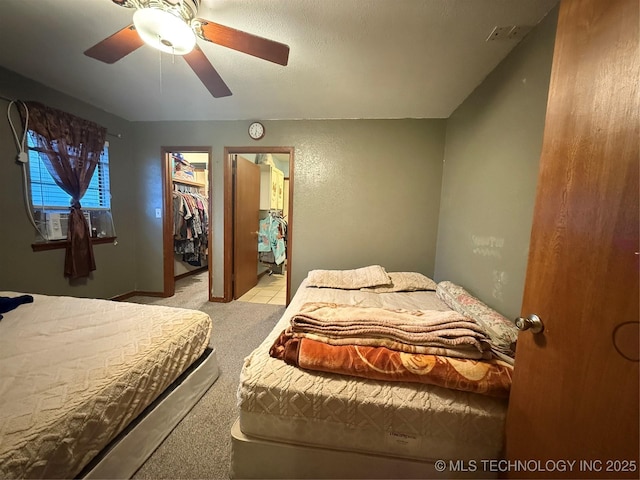 carpeted bedroom with cooling unit, a spacious closet, and ceiling fan