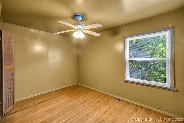 empty room with light hardwood / wood-style flooring, plenty of natural light, and ceiling fan