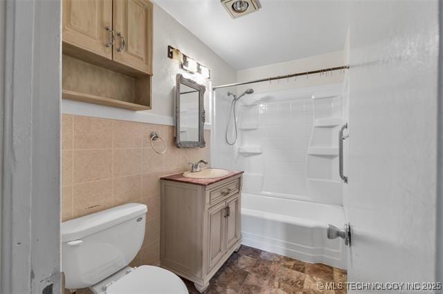 full bathroom with shower / bathtub combination, vanity, toilet, and tile walls