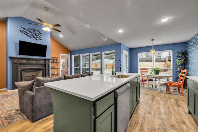 kitchen with dishwasher, sink, hanging light fixtures, light hardwood / wood-style floors, and a center island with sink