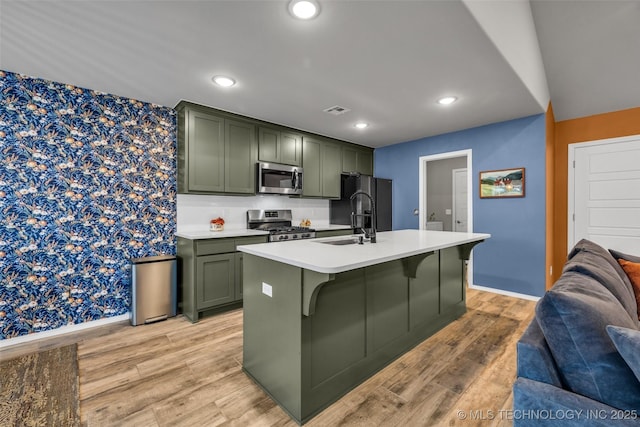 kitchen featuring green cabinets, appliances with stainless steel finishes, sink, and light wood-type flooring