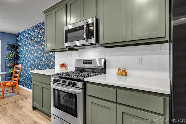 kitchen featuring tasteful backsplash, stainless steel appliances, light hardwood / wood-style floors, and green cabinets