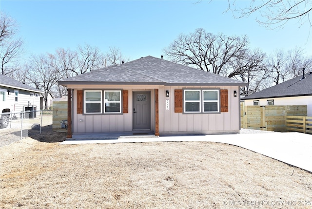 bungalow with roof with shingles, board and batten siding, and fence