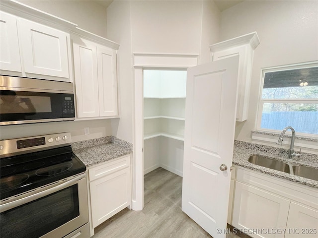 kitchen featuring white cabinetry, sink, light stone counters, and stainless steel appliances