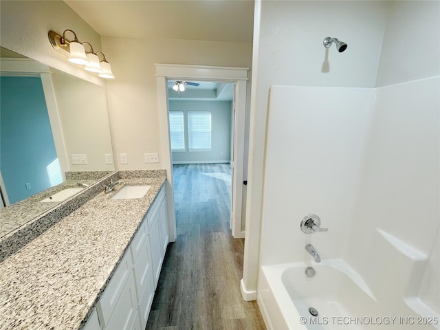 bathroom featuring ceiling fan, wood-type flooring,  shower combination, and vanity