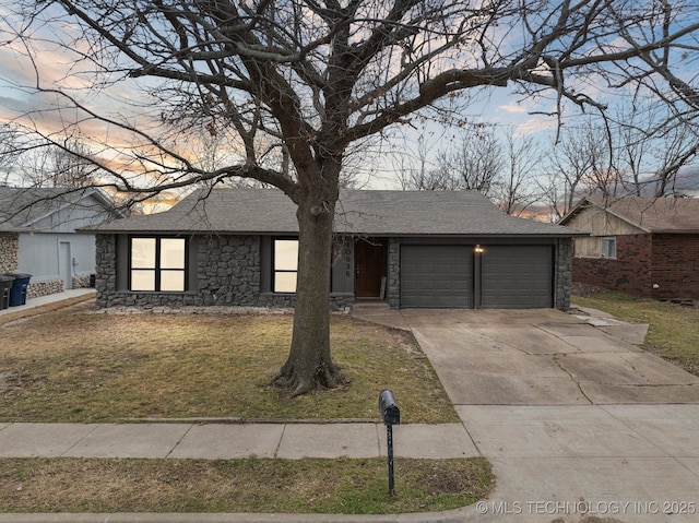 view of front of property featuring concrete driveway, roof with shingles, a yard, a garage, and stone siding