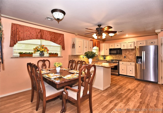 dining room featuring crown molding, ceiling fan, sink, and light hardwood / wood-style floors