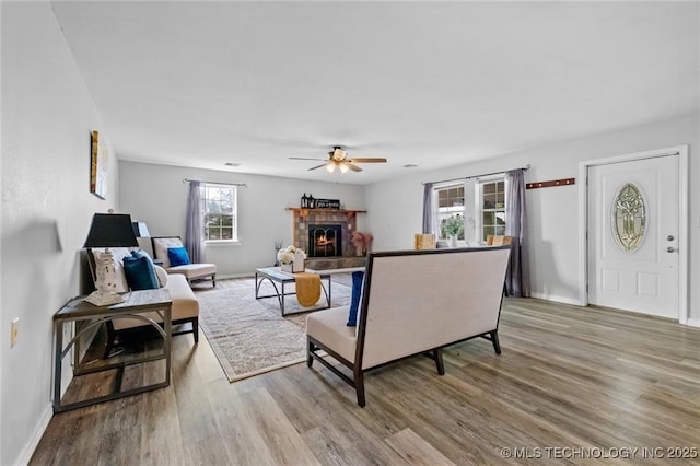 living room with ceiling fan, a fireplace, and light hardwood / wood-style flooring