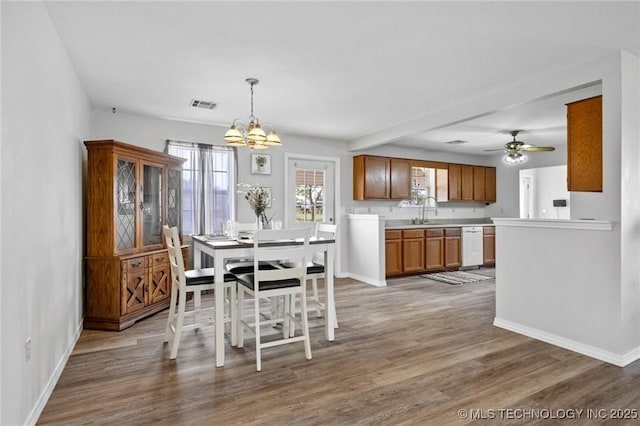 dining space with ceiling fan with notable chandelier, sink, and hardwood / wood-style floors