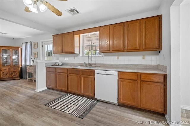 kitchen featuring sink, light hardwood / wood-style flooring, white dishwasher, ceiling fan, and backsplash