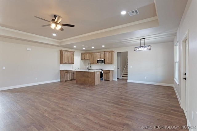 kitchen featuring an island with sink, appliances with stainless steel finishes, a tray ceiling, and pendant lighting