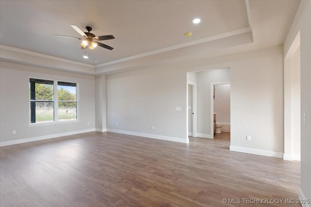 unfurnished room with a tray ceiling, crown molding, ceiling fan, and wood-type flooring