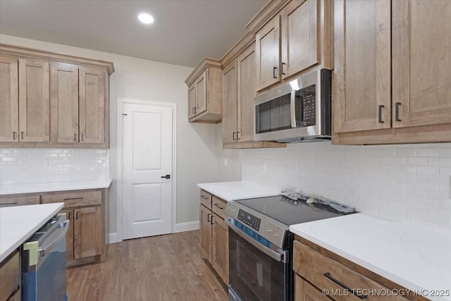 kitchen with light wood-type flooring, stainless steel appliances, and decorative backsplash