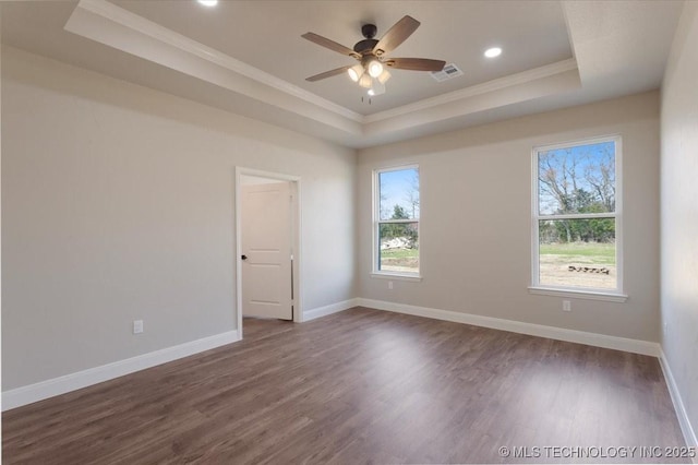 spare room featuring dark hardwood / wood-style floors, a tray ceiling, and ornamental molding