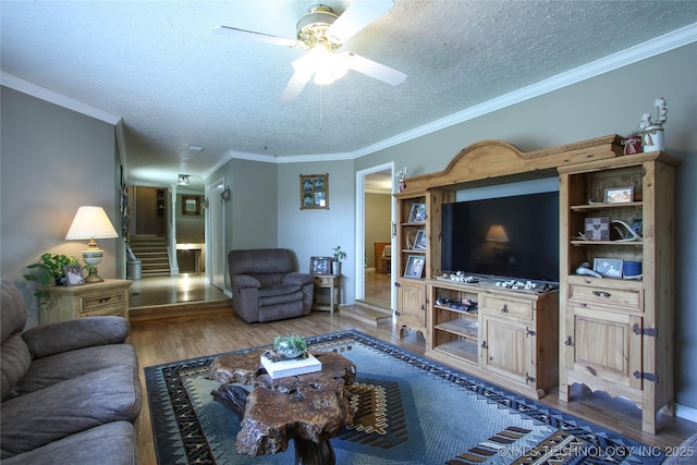 living room with ceiling fan, ornamental molding, wood-type flooring, and a textured ceiling